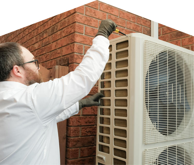 Francis HVAC specialist using a screwdriver to complete a heat pump installation beside a brick wall. Francis HVAC specialist using a screwdriver to complete a heat pump installation beside a brick wall.