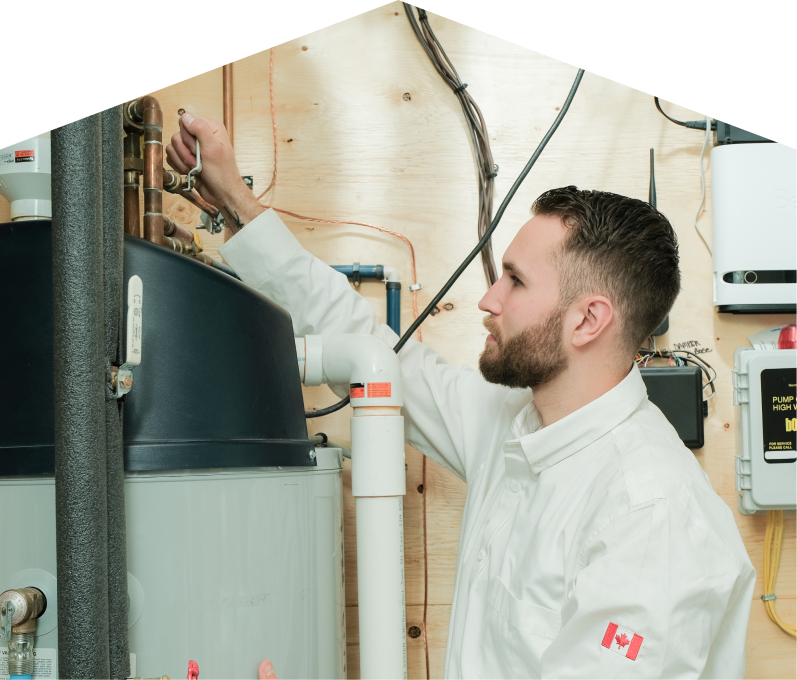 Francis water heater specialist adjusts piping on a large residential unit during a repair service, with exposed wood paneling and mounted utility components in the background.