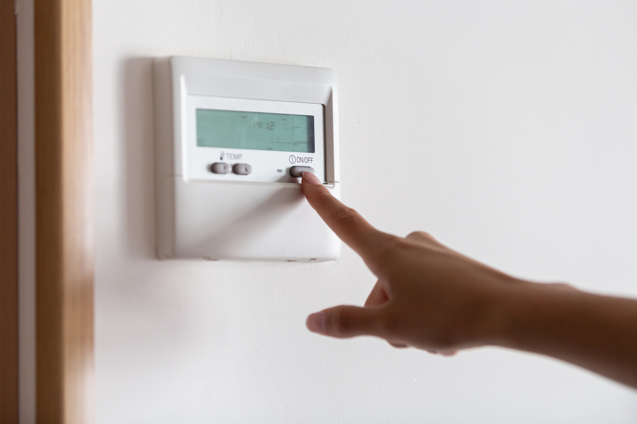 Close-up of a young woman’s hand pressing the on/off button of the air conditioner or heater Close-up of a young woman’s hand pressing the on/off button of the air conditioner or heater