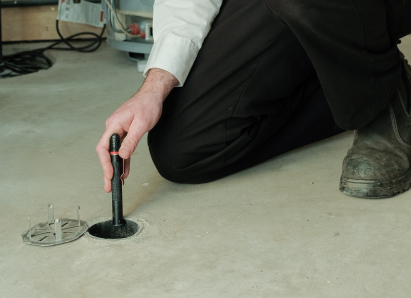 Francis service personnel inserting a diagnostic tool into a floor drain for a residential drain and sewer service check.
