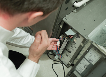 A Francis heating technician inspecting internal wiring during a service check on a residential heating unit.