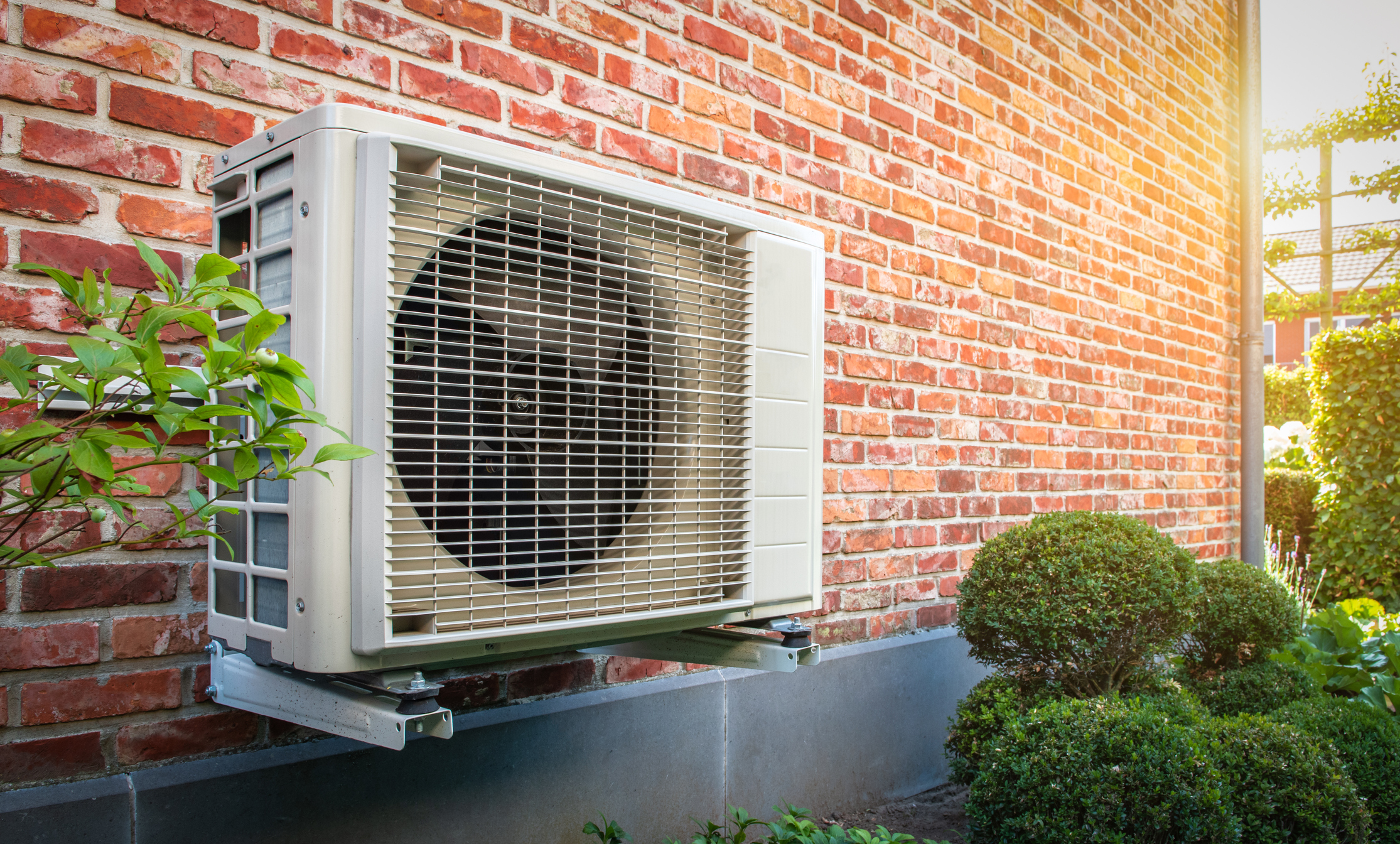 Air conditioning heat pump outdoor unit against brick wall. Air conditioning heat pump outdoor unit against brick wall.