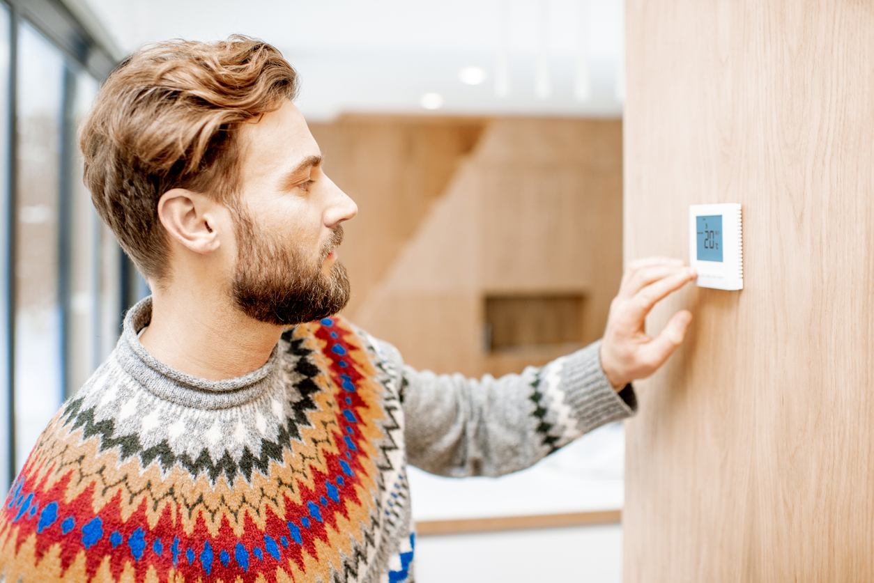 Man adjusting temperature with thermostat at home Man adjusting temperature with thermostat at home