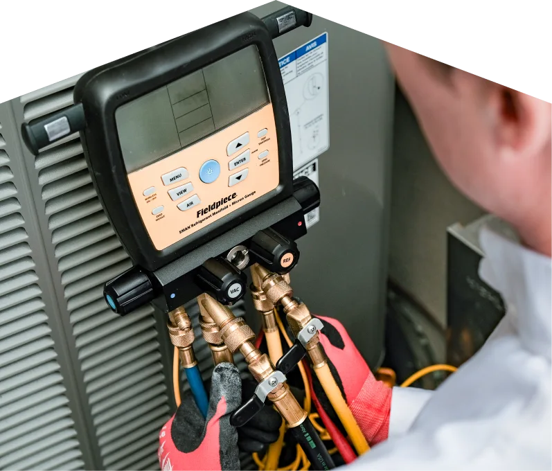 hvac-services-hamilton-webp A Francis home service crew member uses a digital manifold gauge to check refrigerant levels on an HVAC unit for service.